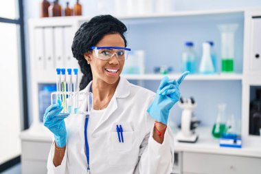 Orta yaşlı İspanyol kadın, laboratuvarda çalışıyor. Gülümsüyor, gülümsüyor. 