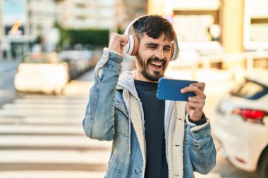 Young hispanic man smiling confident playing video game at street