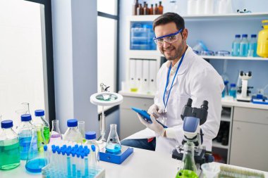 Laboratuvarda çalışan Latin asıllı genç bilim adamı touchpad kullanıyor.