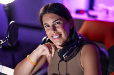 Genç, güzel İspanyol kadın, gülümseyen, kendine güvenen, oyun masasında oturan.