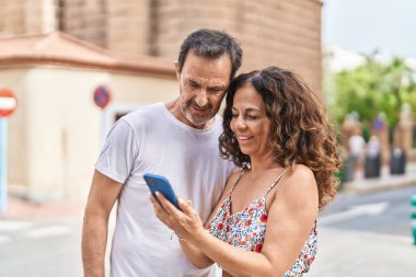 Man and woman couple smiling confident using smartphone at street