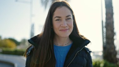 Sokakta kendine güvenen beyaz kadın gülümsüyor.