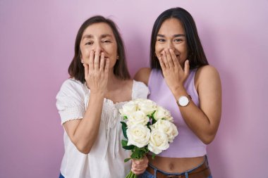 İspanyol anne ve kızı ellerinde bir buket beyaz çiçekle gülüyor ve utanıyor kıkırdıyor ağızlarını ellerle, dedikoduyla ve skandal konseptiyle kapatıyor. 