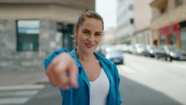 Young woman smiling confident pointing with finger at street