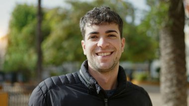 Young hispanic man smiling confident at park
