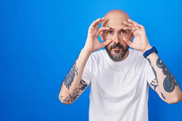 Spaanse Man Met Tatoeages Blauwe Achtergrond Die Probeert Ogen Openen — Stockfoto