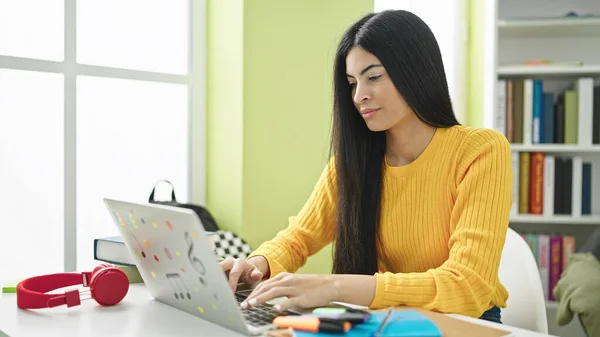 図書館大学でノートパソコンを勉強している若い美しいヒスパニック系女性の学生 — ストック写真