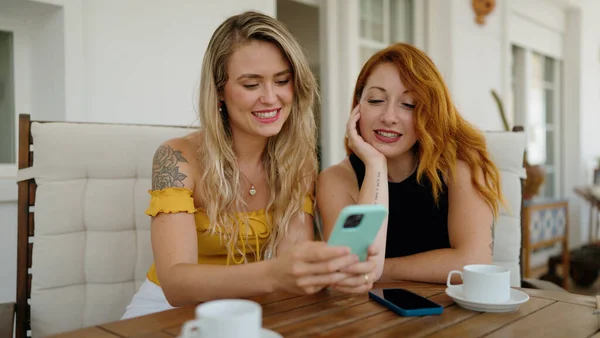 Δύο Γυναίκες Που Χρησιμοποιούν Smartphone Και Πίνοντας Καφέ Κάθονται Στο — Φωτογραφία Αρχείου