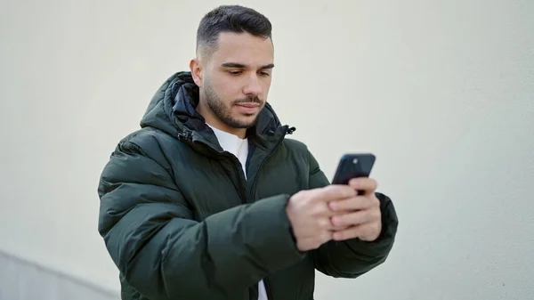Молодой Латиноамериканец Использует Смартфон Серьезным Выражением Изолированном Белом Фоне — стоковое фото