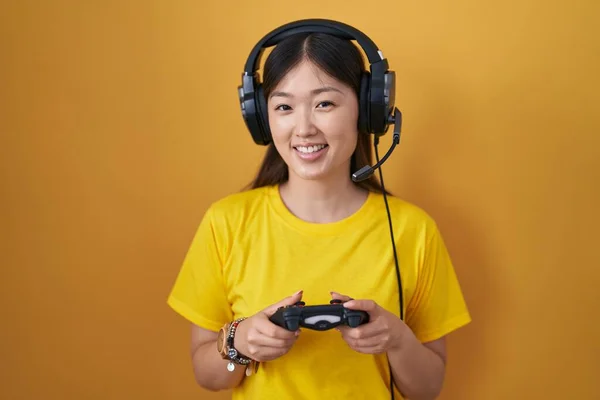 中国年轻女子在玩电子游戏时 手里拿着控制器 脸上带着快乐而沉着的笑容 幸运的人 — 图库照片