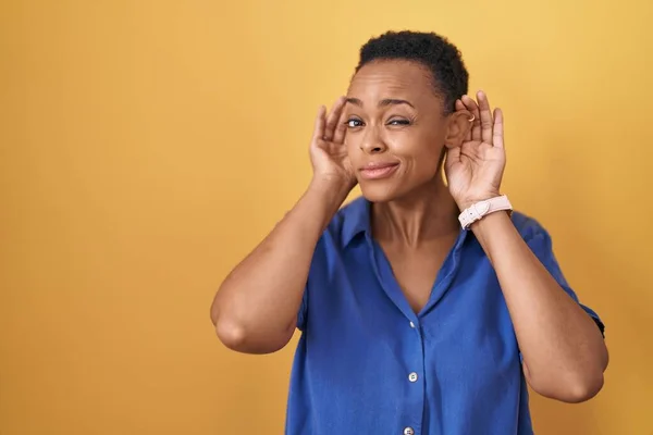 Африканская Американка Стоящая Жёлтом Фоне Пытаясь Услышать Жесты Ушей Обеими — стоковое фото