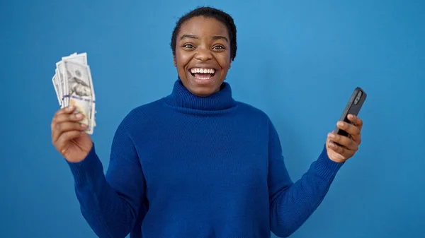 Afro Amerikaanse Vrouw Glimlachend Met Dollars Smartphone Geïsoleerde Blauwe Achtergrond — Stockfoto