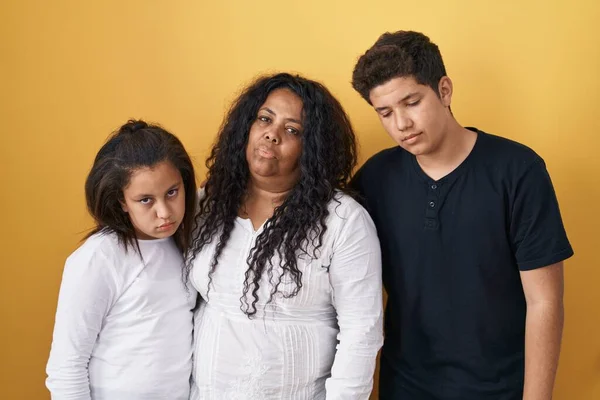 母親と娘と息子の家族が黄色の背景の上に立って眠いと疲れて 疲労とたまり場のために疲れ 朝の怠惰な目 — ストック写真