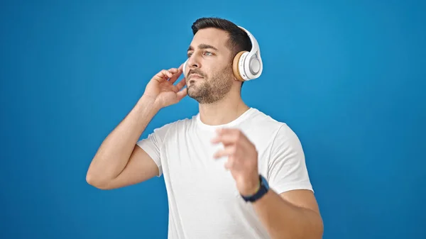 Jonge Spaanse Man Luisteren Naar Muziek Geïsoleerde Blauwe Achtergrond — Stockfoto