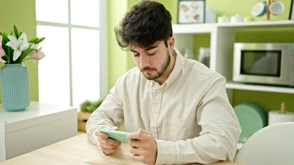 Jonge Spaanse Man Kijken Naar Video Smartphone Zitten Tafel Eetkamer — Stockfoto