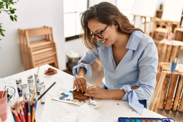 年轻美丽的惊慌失措的女画家微笑着自信地用手在艺术工作室里做陶瓷壶 — 图库照片