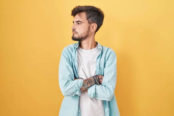 Joven Hombre Hispano Con Tatuajes Pie Sobre Fondo Amarillo Mirando — Foto de Stock