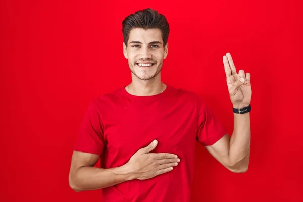 Jovem Hispânico Sobre Fundo Vermelho Sorrindo Jurando Com Mão Peito — Fotografia de Stock