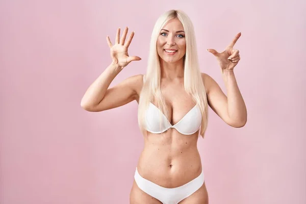 Beyaz Kadın Pembe Arka Planda Çamaşırı Giyiyor Yedinci Parmaklarıyla Işaret — Stok fotoğraf