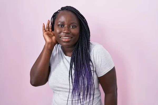 Молодая Африканская Женщина Стоящая Розовом Фоне Улыбаясь Рукой Над Ухом — стоковое фото