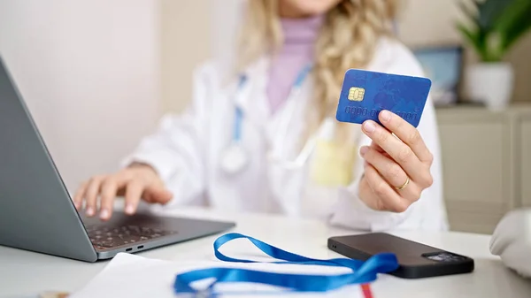 带着手提电脑和信用卡在诊所购物的金发女医生 — 图库照片