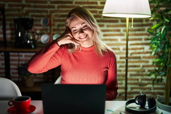Blonde Vrouw Die Avonds Thuis Een Laptop Gebruikt Glimlachend Telefoongebaar — Stockfoto