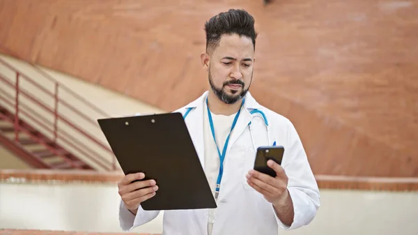 Mladý Latin Muž Lékař Pomocí Smartphone Držení Schránky Nemocnici — Stock fotografie