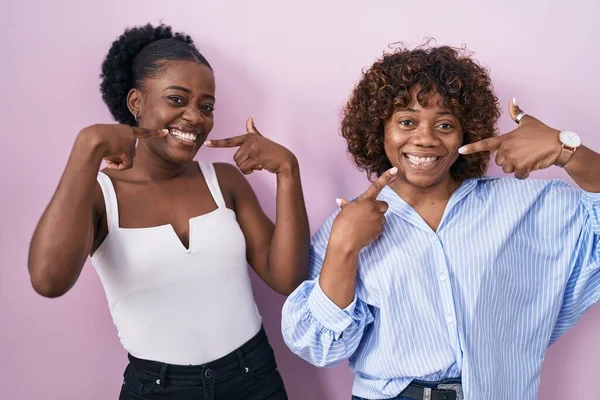 Duas Mulheres Africanas Sobre Fundo Rosa Sorrindo Alegre Mostrando Apontando — Fotografia de Stock