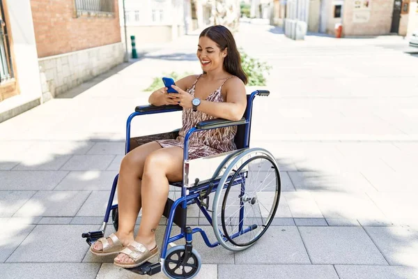 年轻美丽的惊慌失措的女人坐在街上的轮椅上用智能手机 — 图库照片