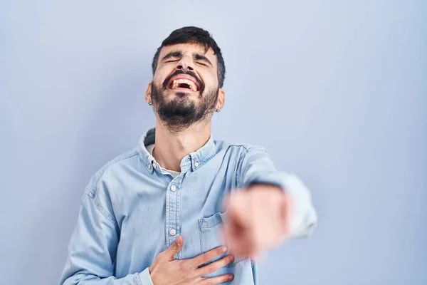 Joven Hispano Con Barba Pie Sobre Fondo Azul Riéndose Señalando —  Fotos de Stock