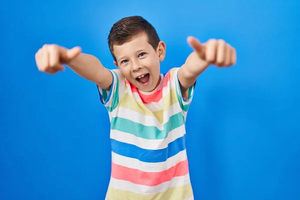 年轻的高加索小孩站在蓝色的背景上 赞成用手做积极的手势 微笑着竖起大拇指 为成功感到高兴 优胜手势 — 图库照片