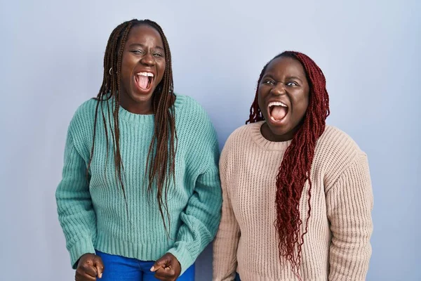 青の背景に立っている2人のアフリカ人女性は怒りと怒りで叫び 不満と怒りを叫びました 怒りと攻撃的な考え方 — ストック写真