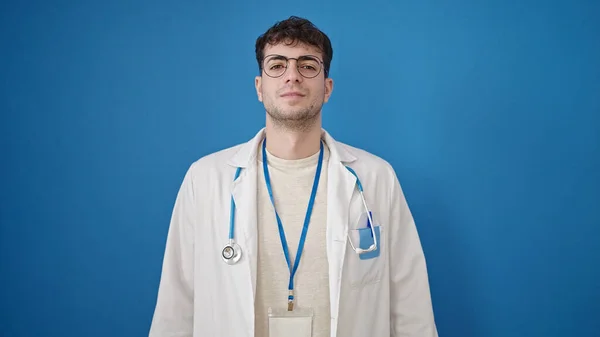 若いですヒスパニック男医師立っています深刻な表現上の隔離された青の背景 — ストック写真