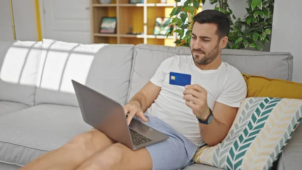 Молодий Іспаномовний Чоловік Купує Ноутбуком Кредитною Карткою Сидячи Дивані Вдома — стокове фото