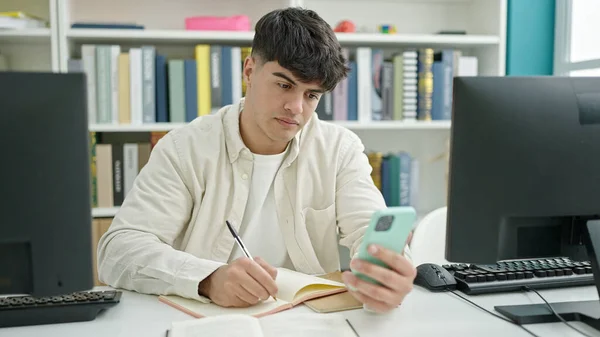 Mladý Hispánec Muž Student Pomocí Smartphone Psaní Poznámek Knihovně — Stock fotografie