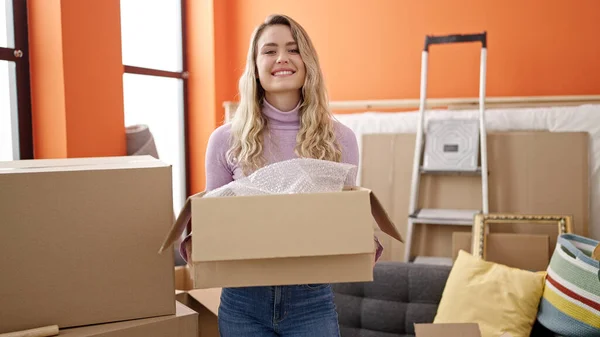 stock image Young blonde woman smiling confident holding package at new home