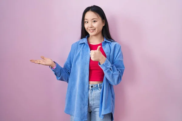 Молодая Азиатка Стоящая Розовом Фоне Показывая Ладонь Делая Хорошо Жест — стоковое фото