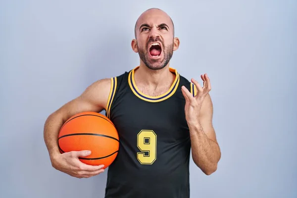 年轻的秃头男子 留着胡子 身穿篮球服 疯狂地拿着球 疯狂地喊叫着 带着咄咄逼人的表情和手臂大喊大叫 沮丧的概念 — 图库照片