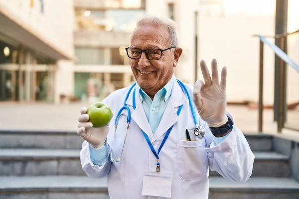 Starszy Lekarz Siwymi Włosami Trzymając Zdrowe Zielone Jabłko Robi Znak — Zdjęcie stockowe