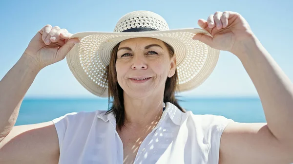 Turista Hispana Mediana Edad Sonriendo Sosteniendo Sombrero Verano Playa —  Fotos de Stock