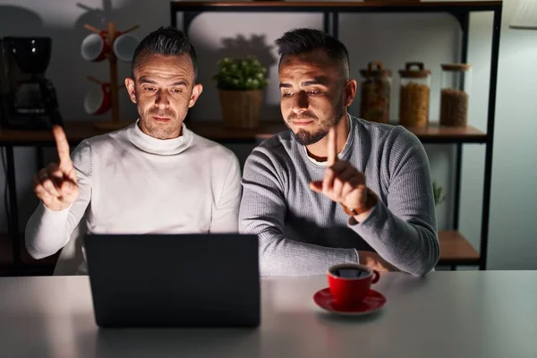 stock image Homosexual couple using computer laptop pointing with finger up and angry expression, showing no gesture 