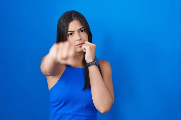 積極的かつ怒りの攻撃 脅威と暴力のために青色の背景パンチング拳上に立つヒスパニック女性 — ストック写真