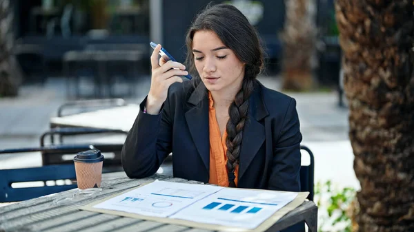 若い美しいヒスパニック系女性のビジネスワーカーは コーヒーショップテラスでスマートフォン読書文書によって音声メッセージを送信します — ストック写真