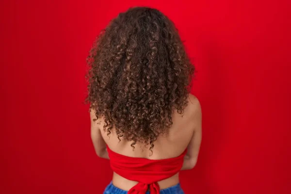 Spaanse Vrouw Met Krullend Haar Staande Rode Achtergrond Naar Achteren — Stockfoto