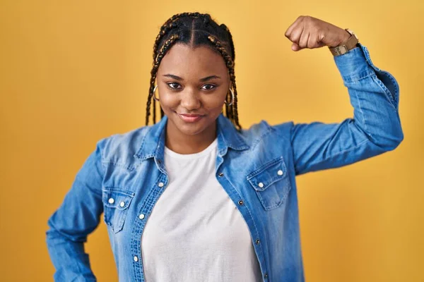 Африканская Американка Косичками Стоящая Желтом Фоне Сильный Человек Показывает Мышцы — стоковое фото