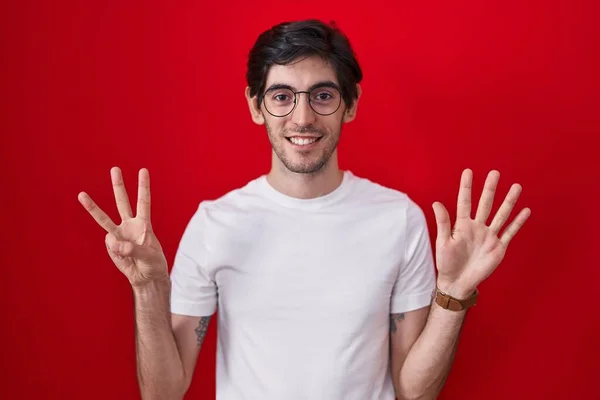 Молодий Іспаномовний Чоловік Стоїть Над Червоним Тлом Показуючи Вказуючи Пальцями — стокове фото