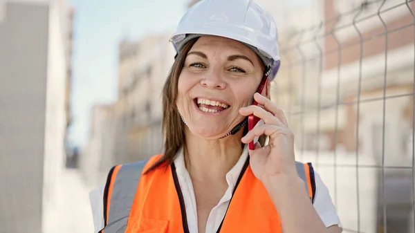 建設現場でスマートフォンで話している中世のヒスパニック女性ビルダー — ストック写真