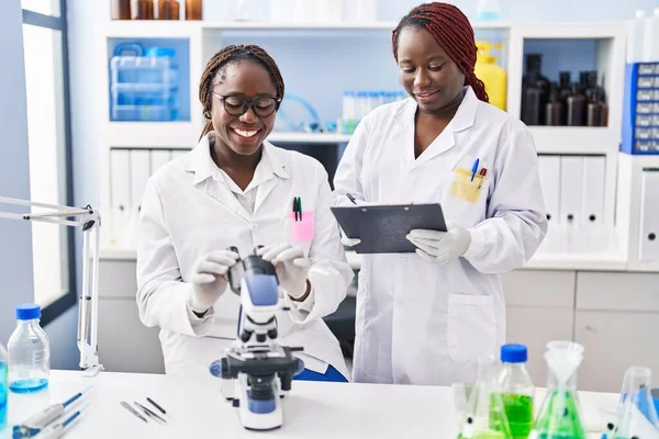 アフリカ系アメリカ人女性科学者は研究室で文書に顕微鏡を使って — ストック写真