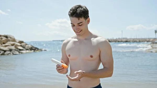 Junger Hispanischer Mann Lächelt Selbstbewusst Und Trägt Sonnencreme Strand Auf — Stockfoto