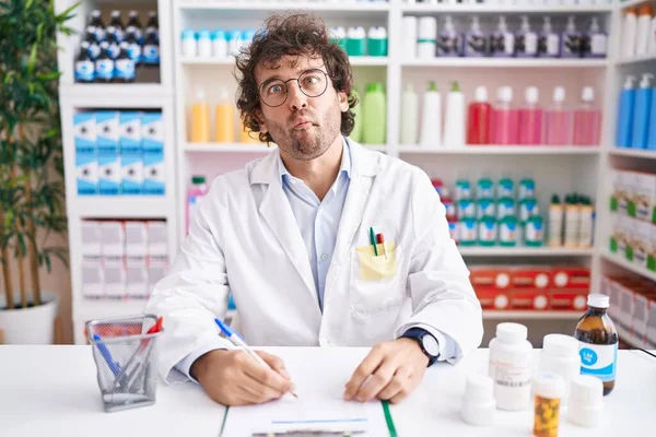 Joven Hispano Trabajando Farmacia Haciendo Cara Pez Con Labios Gesto —  Fotos de Stock
